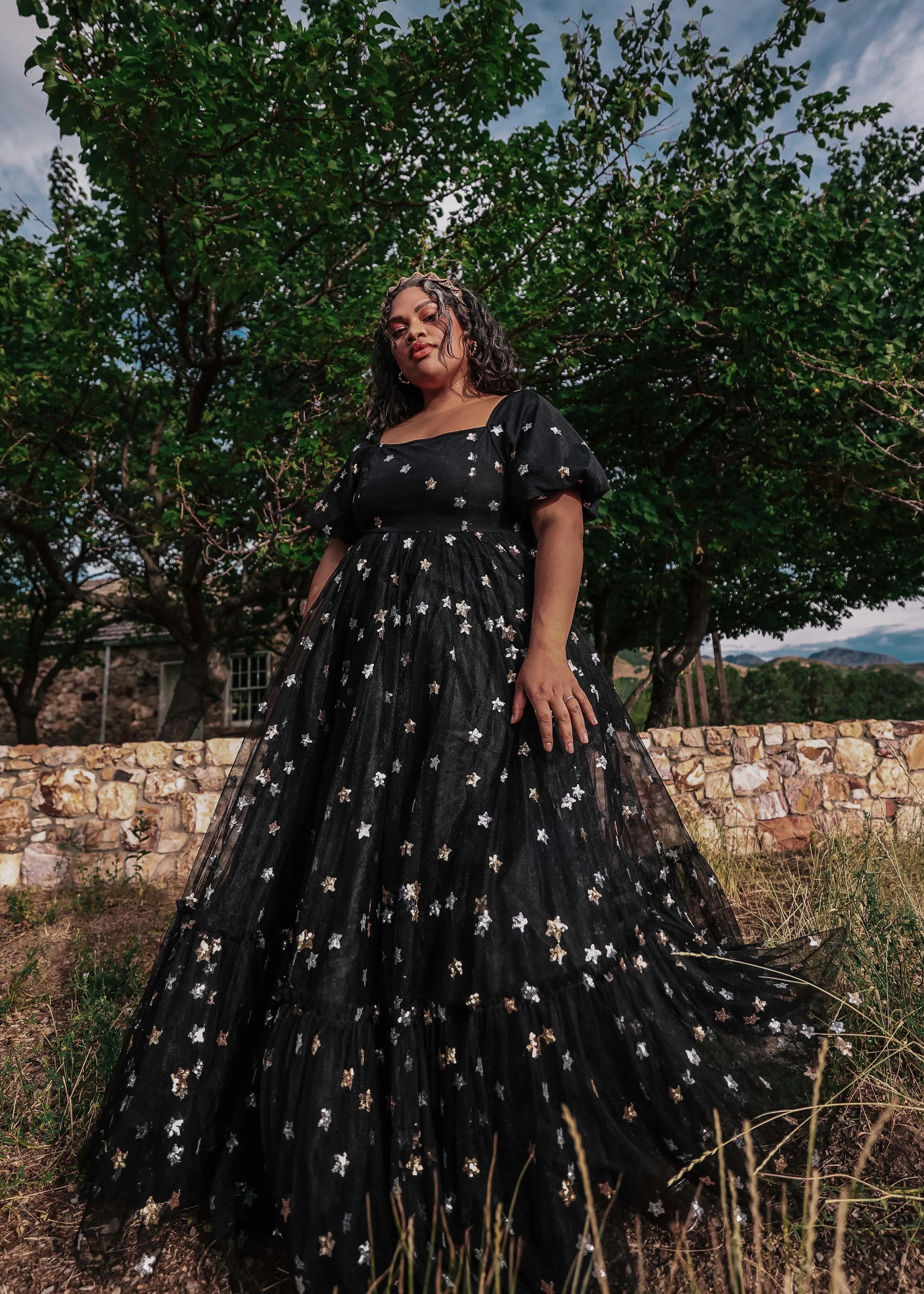 Black Wendy Dress by JessaKae featuring star pattern, sleeveless design, and fitted waist on a model.
